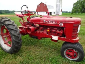 En röd klassisk vintage McCormick Farmall-traktor på en auktion.