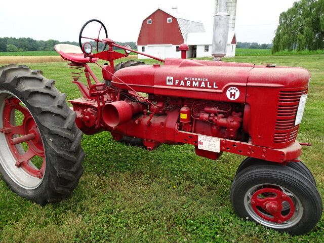 En röd klassisk vintage McCormick Farmall-traktor på en auktion.